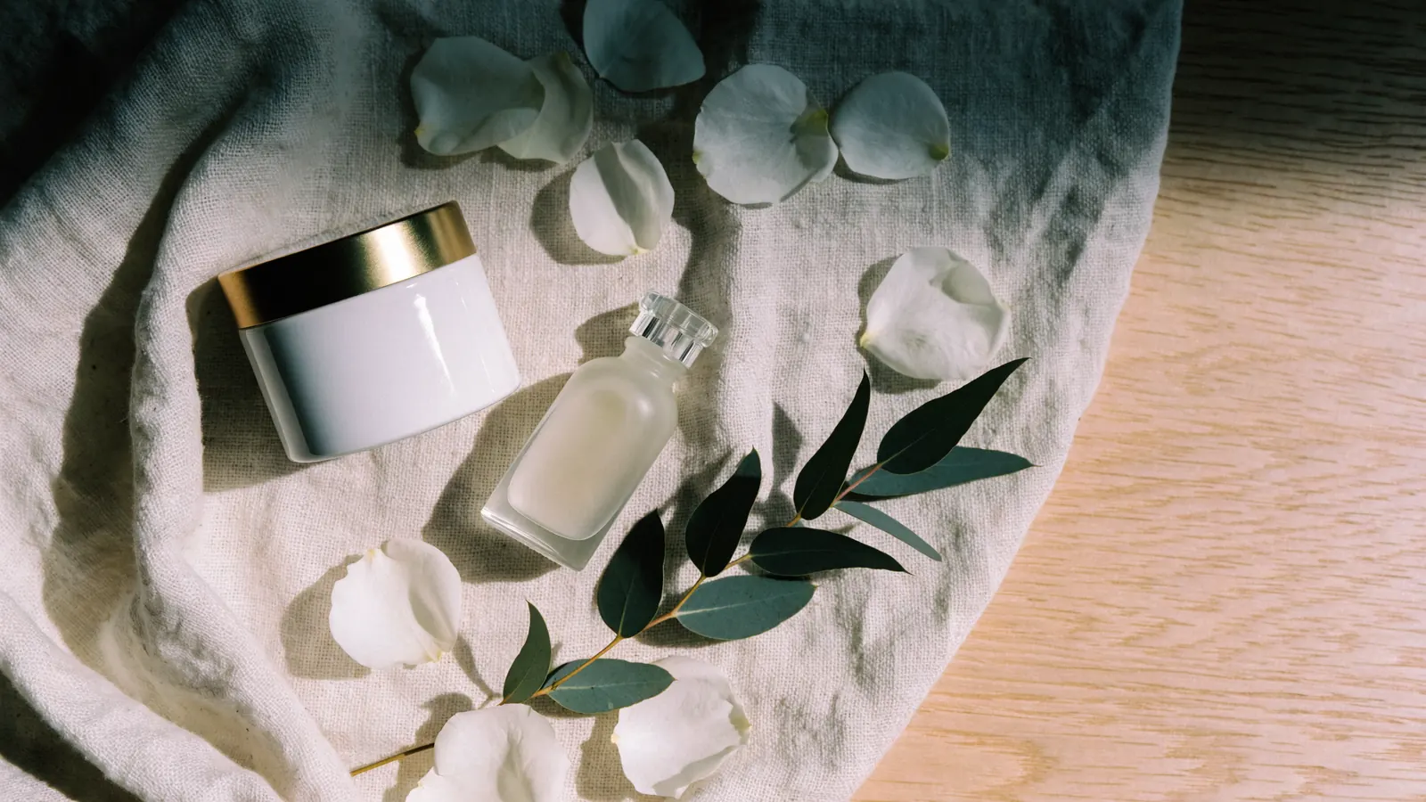 Ram de flors blanques, pot de crema i rames d'eucaliptus sobre lli clar